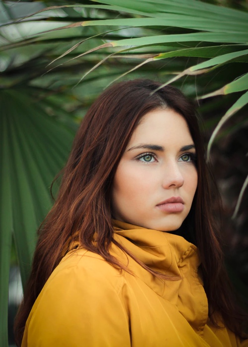 photo of young women with her face directed to the right on a background of green leaves